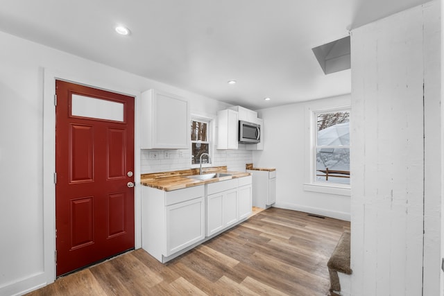 kitchen with wood counters, white cabinets, tasteful backsplash, and sink