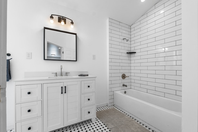 bathroom with vaulted ceiling, tile patterned flooring, tiled shower / bath, and vanity