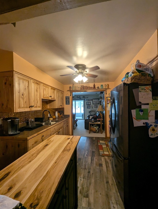 kitchen with ceiling fan, black fridge, sink, dark wood-type flooring, and wood counters