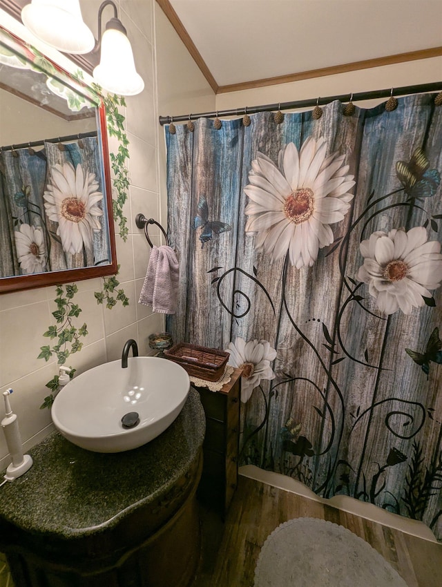 bathroom with walk in shower, tile walls, decorative backsplash, sink, and crown molding