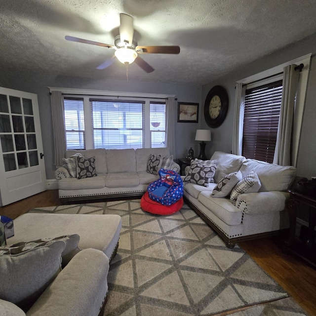 living room with a textured ceiling, ceiling fan, and wood-type flooring