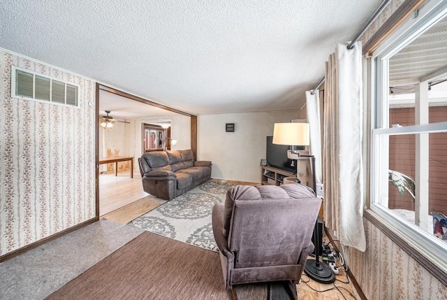 living room featuring ceiling fan, a textured ceiling, and light hardwood / wood-style flooring