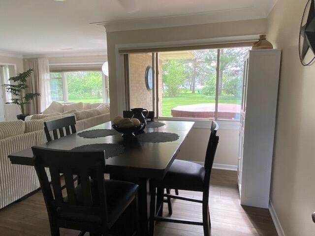 dining space with a wealth of natural light, ornamental molding, and hardwood / wood-style floors