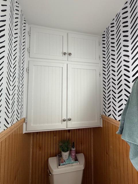 bathroom featuring toilet and wooden walls