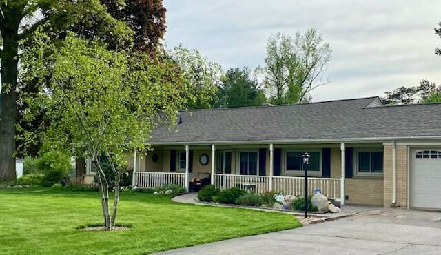 ranch-style house with a front lawn, covered porch, and a garage