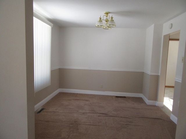 unfurnished room featuring a chandelier and light colored carpet