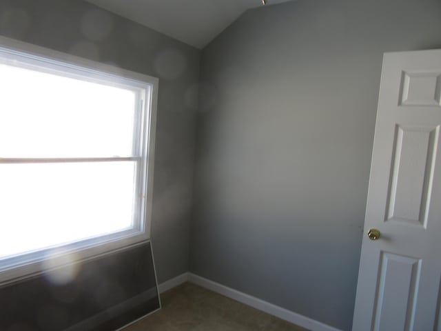 unfurnished room featuring lofted ceiling