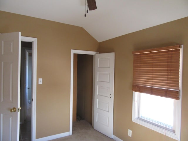 unfurnished bedroom featuring vaulted ceiling, ceiling fan, a closet, and light carpet