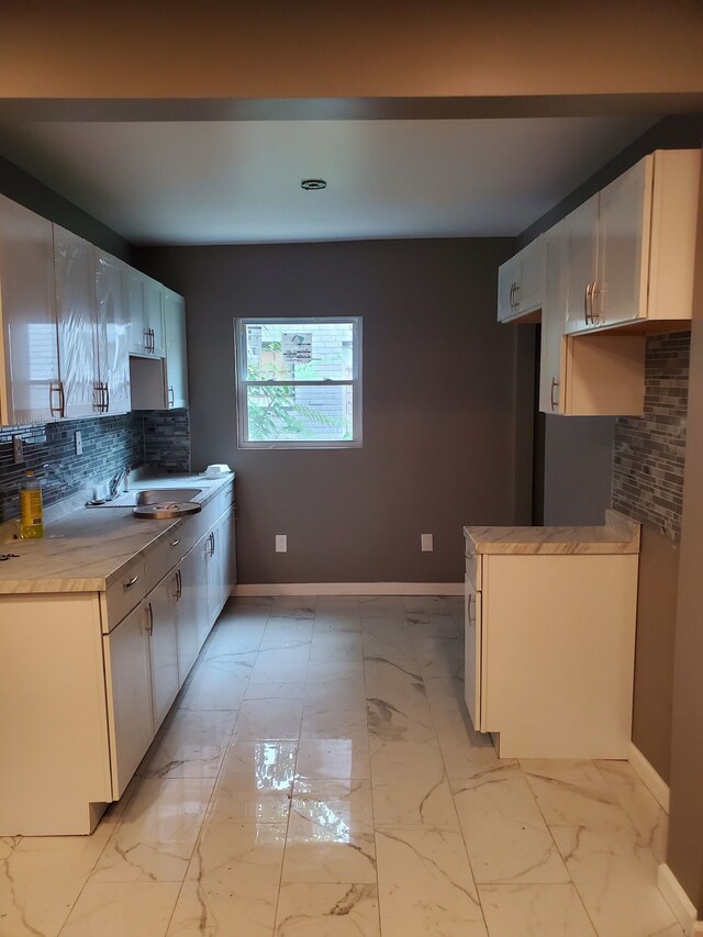 kitchen featuring decorative backsplash, white cabinets, and sink