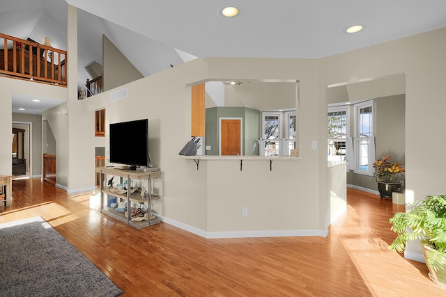 living room featuring high vaulted ceiling and light hardwood / wood-style floors