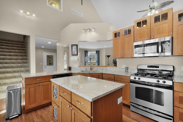 kitchen with sink, light hardwood / wood-style flooring, kitchen peninsula, a kitchen island, and stainless steel appliances