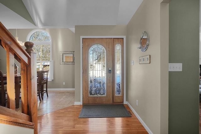 foyer entrance featuring light hardwood / wood-style flooring, a healthy amount of sunlight, and vaulted ceiling