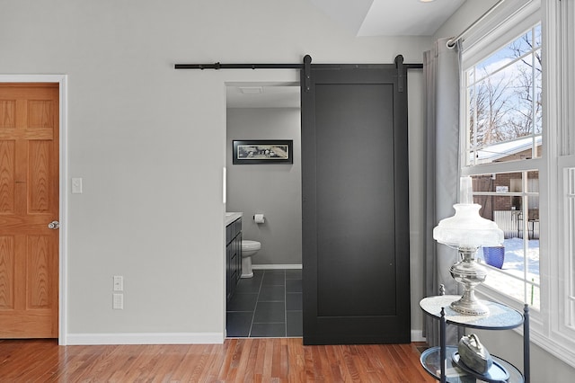 interior space with a barn door, dark hardwood / wood-style flooring, and ensuite bath