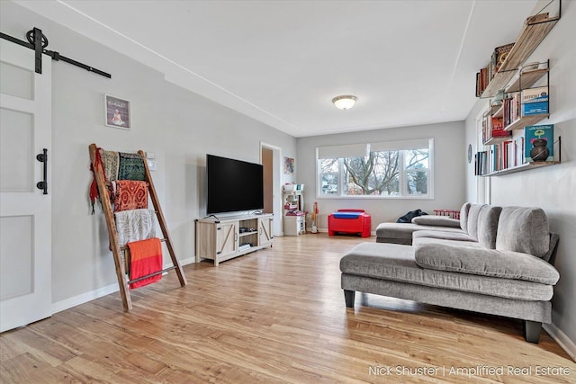 living room with a barn door and light wood-type flooring