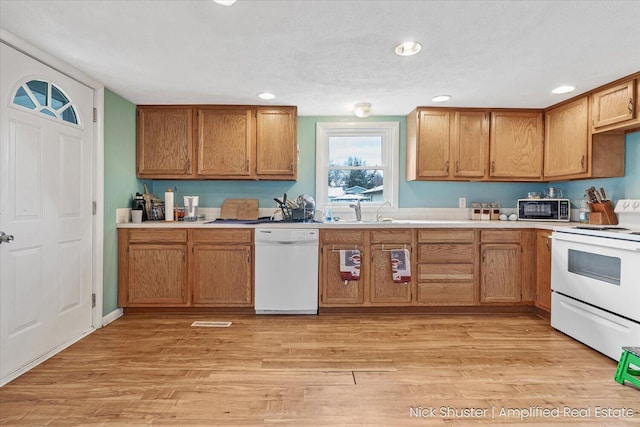 kitchen featuring light wood-type flooring, a textured ceiling, sink, and white appliances