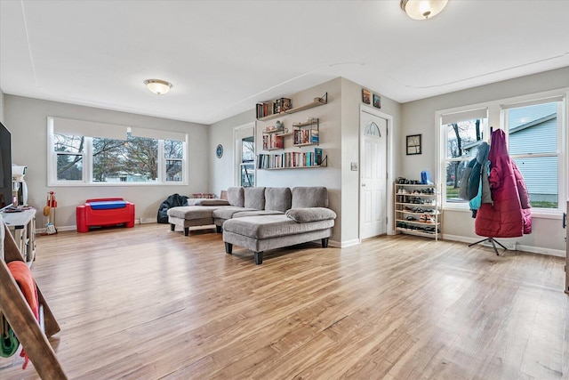 living room featuring light wood finished floors, healthy amount of natural light, and baseboards