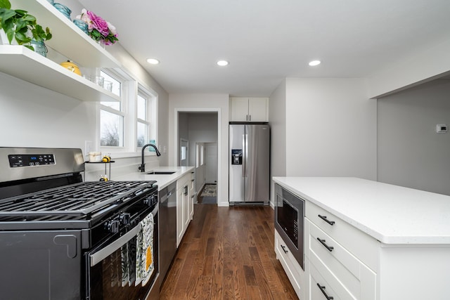 kitchen with dark wood-type flooring, sink, stainless steel appliances, and white cabinetry