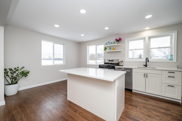 kitchen featuring stainless steel appliances, dark hardwood / wood-style floors, a kitchen island, white cabinets, and sink