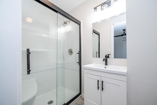 bathroom with vanity, ceiling fan, and a shower with door