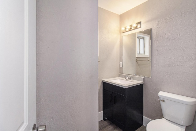 bathroom with toilet, vanity, and wood-type flooring