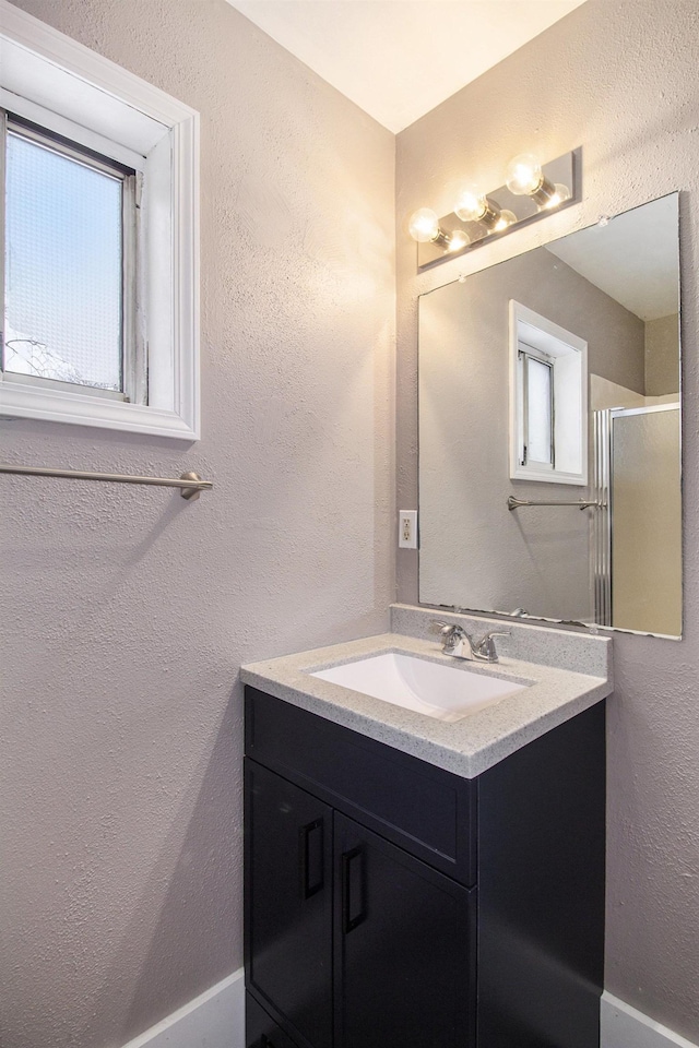 bathroom featuring a shower with shower door and vanity