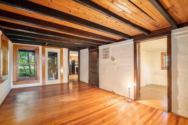 spare room with beam ceiling and light hardwood / wood-style floors