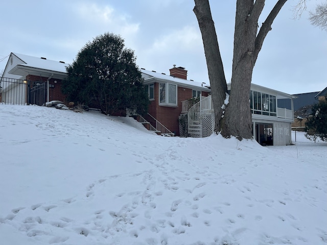 yard layered in snow featuring a sunroom