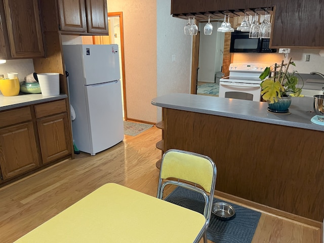 kitchen with light hardwood / wood-style flooring and white appliances