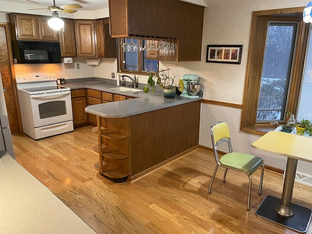 kitchen featuring light hardwood / wood-style floors, kitchen peninsula, ceiling fan, electric stove, and sink