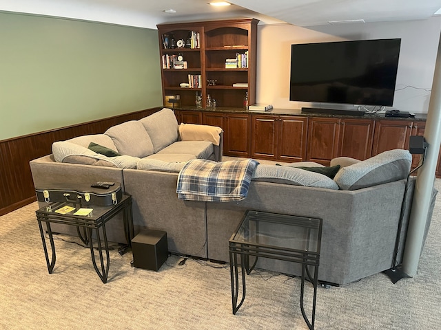 carpeted living room with wood walls