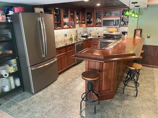 bar with decorative light fixtures, sink, wooden walls, and stainless steel appliances