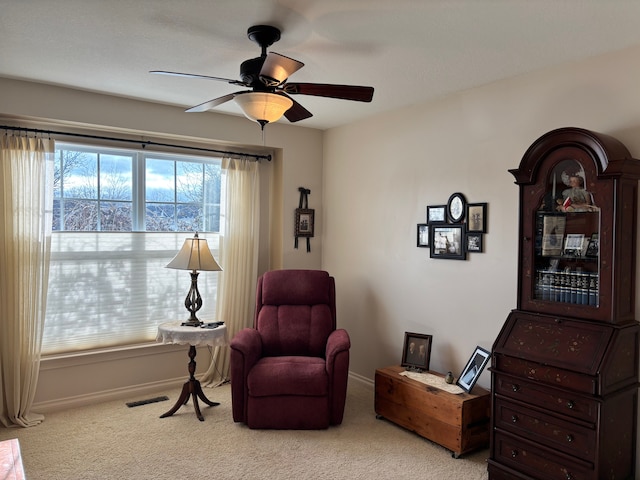 living area with a wealth of natural light, light carpet, and ceiling fan