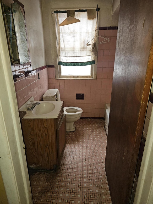 bathroom featuring tile walls, toilet, vanity, and a bathing tub