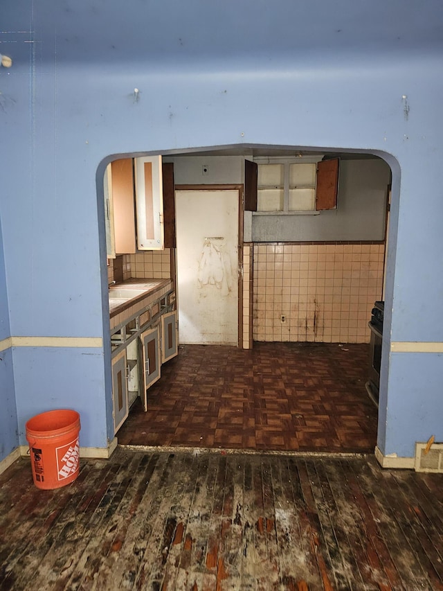 kitchen with stainless steel range, backsplash, and dark parquet flooring