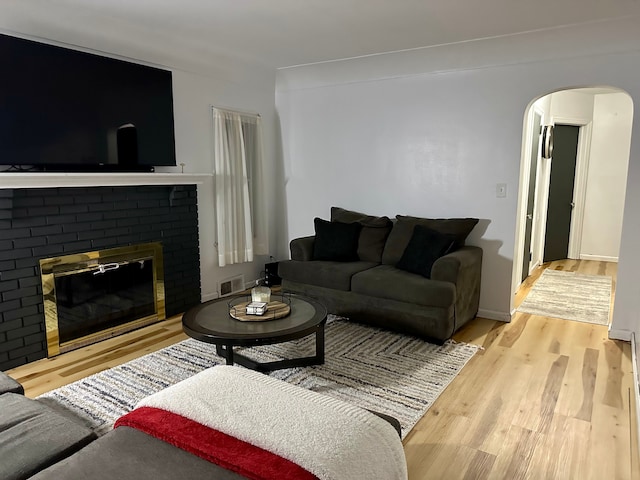 living room featuring a brick fireplace and light hardwood / wood-style flooring