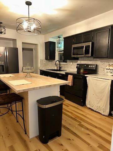 kitchen with appliances with stainless steel finishes, a center island, a chandelier, pendant lighting, and sink