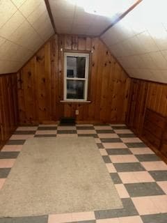 additional living space featuring vaulted ceiling and wood walls