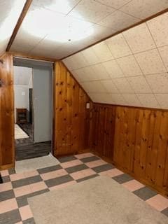 bonus room with lofted ceiling and wood walls