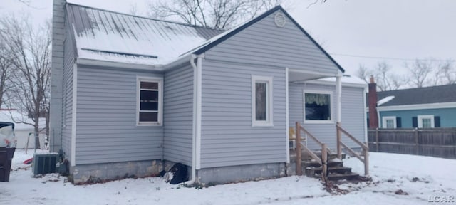 snow covered rear of property with central air condition unit