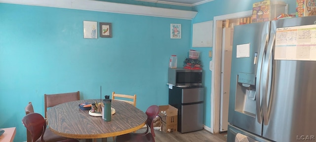 dining space with light wood-type flooring and ornamental molding