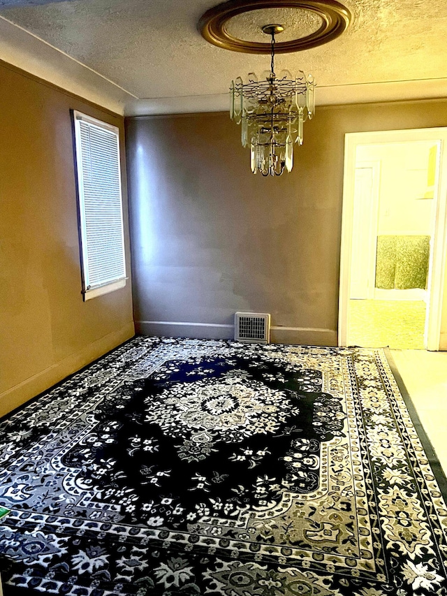 empty room with a textured ceiling and a chandelier