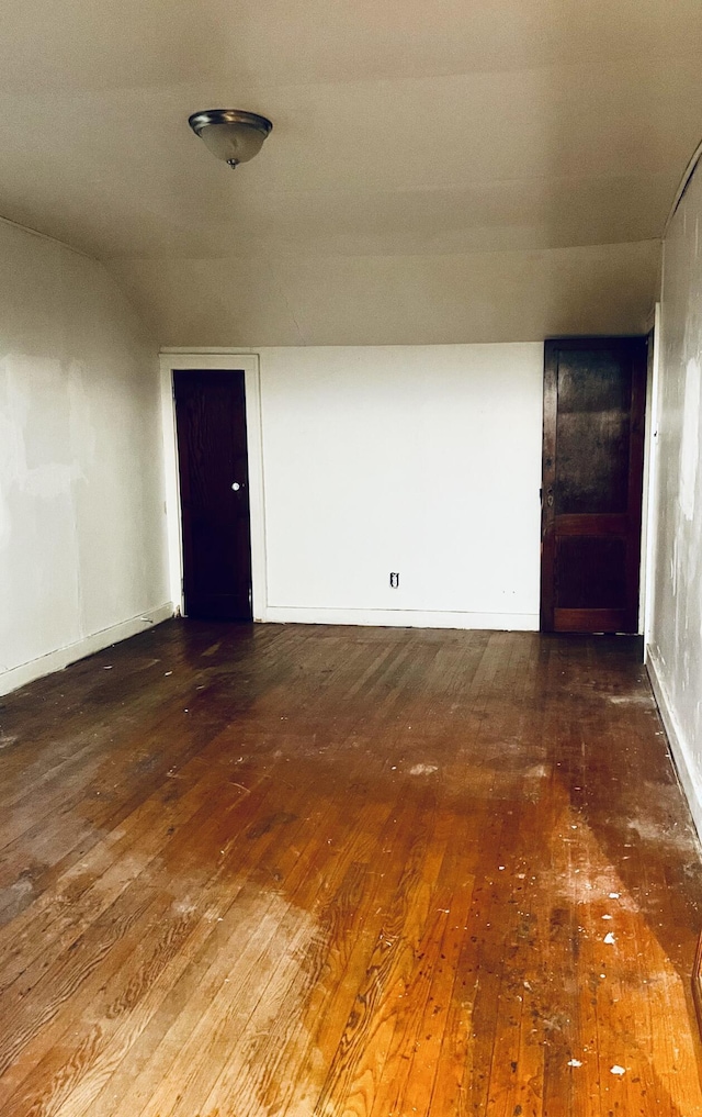 unfurnished room with dark wood-type flooring and lofted ceiling