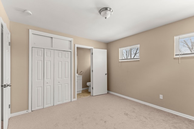 unfurnished bedroom with multiple windows, ensuite bathroom, and a closet