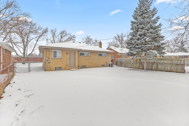 snow covered back of property featuring central AC unit