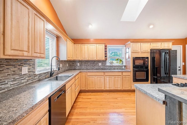 kitchen with tasteful backsplash, light brown cabinetry, black appliances, light hardwood / wood-style flooring, and sink