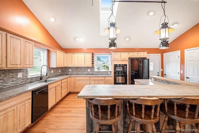 kitchen with sink, black appliances, light brown cabinets, and decorative light fixtures