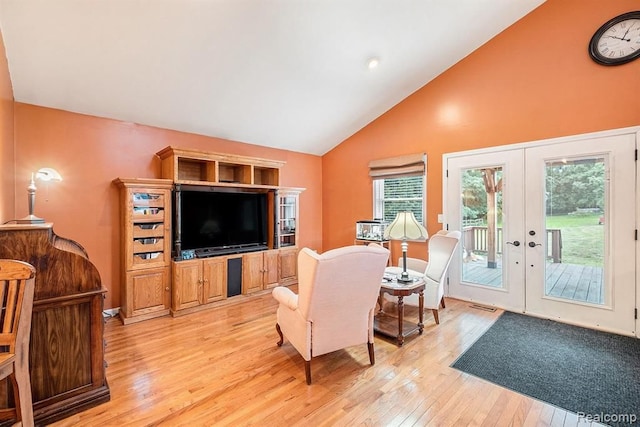 living room featuring light wood-type flooring, french doors, and high vaulted ceiling