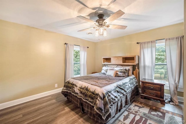 bedroom featuring ceiling fan, multiple windows, and wood-type flooring