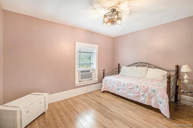 bedroom with cooling unit and light hardwood / wood-style flooring