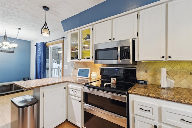 kitchen with decorative light fixtures, white cabinetry, stainless steel appliances, and a notable chandelier